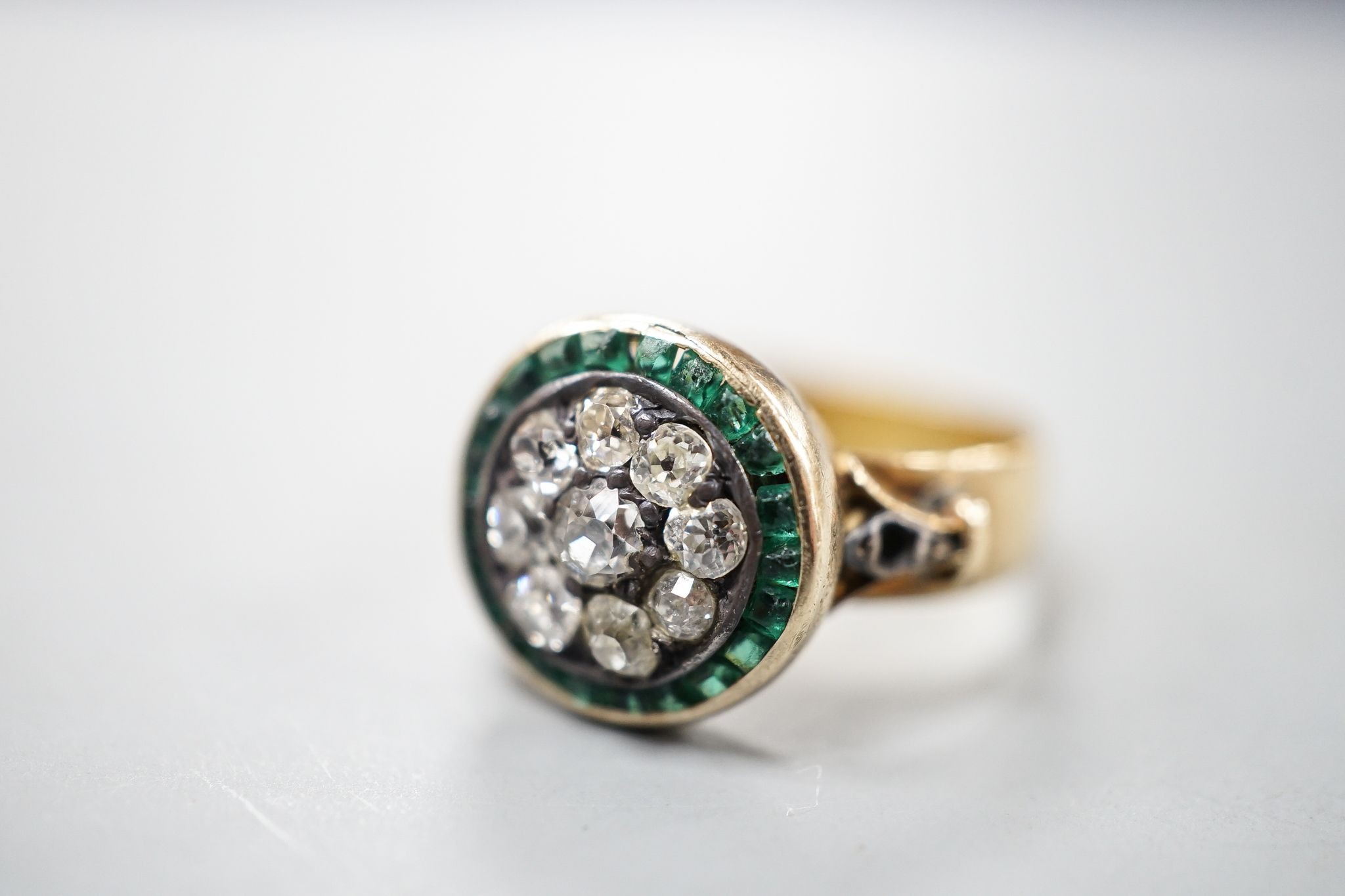 A George V 22ct gold emerald? and diamond set circular cluster ring, the shank with engraved inscription, size N/O, gross weight 5.3 grams.